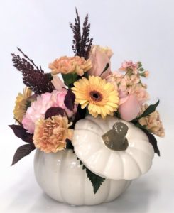 peach and yellow flowers in white ceramic pumpkin