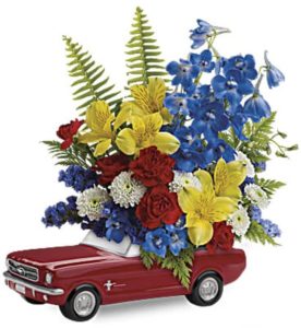 This bright bouquet features yellow alstroemeria, red miniature carnations, white button spray chrysanthemums, blue delphinium, blue sinuata statice, leatherleaf fern and sword fern. Delivered in Teleflora's exclusive '65 Ford Mustang collectible keepsake.
