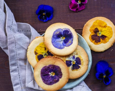 Shortbread cookies with a decor in the form of natural flowers on a dark wooden background
