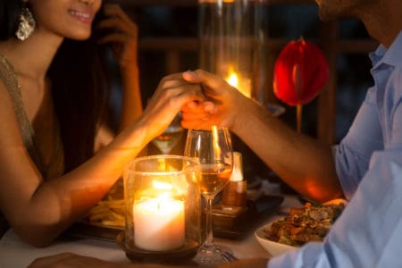 Romantic couple holding hands together over candlelight during romantic dinner